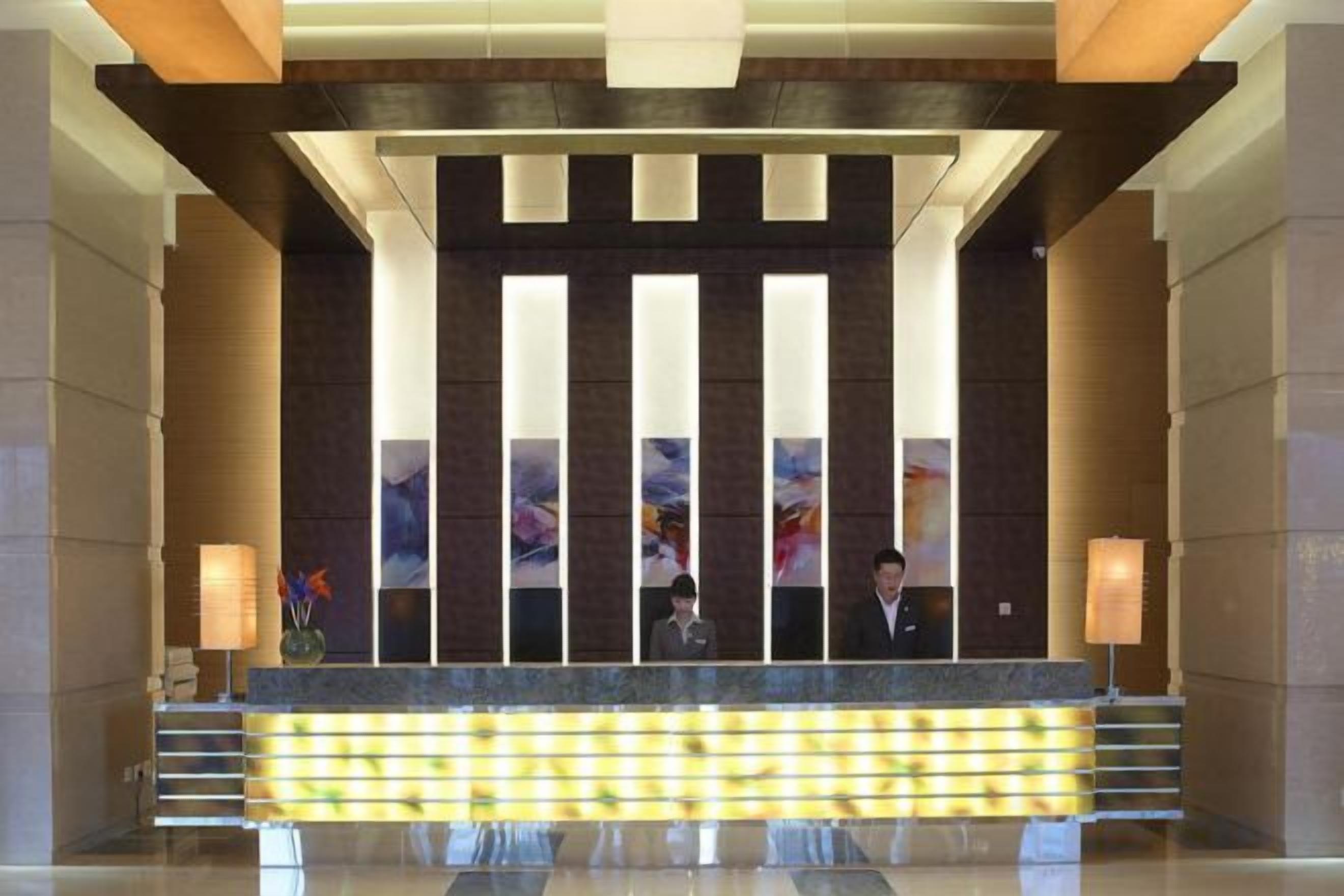 A reception area with a reception desk, two receptionists, and a modern design with vertical light fixtures.