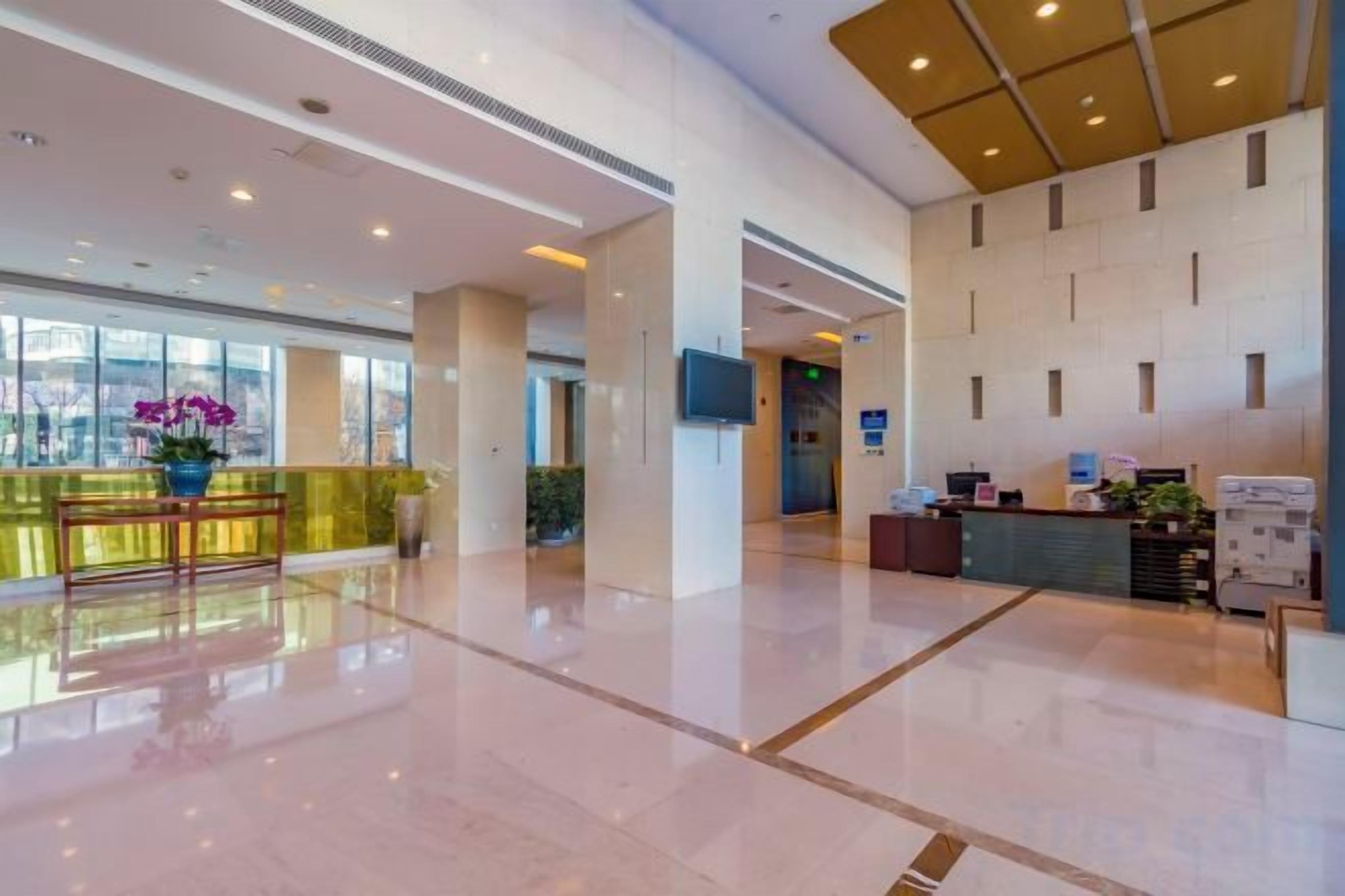 A spacious lobby with a reception desk, a large window, and a plant.