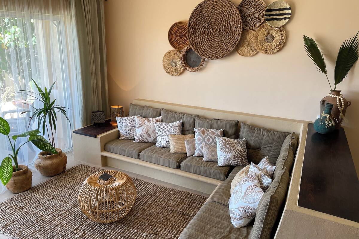 A modern living room with a sofa, decorative wall art, and potted plants.