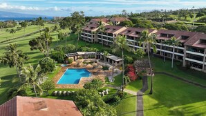 A resort with a swimming pool, lush greenery, and a view of the ocean.