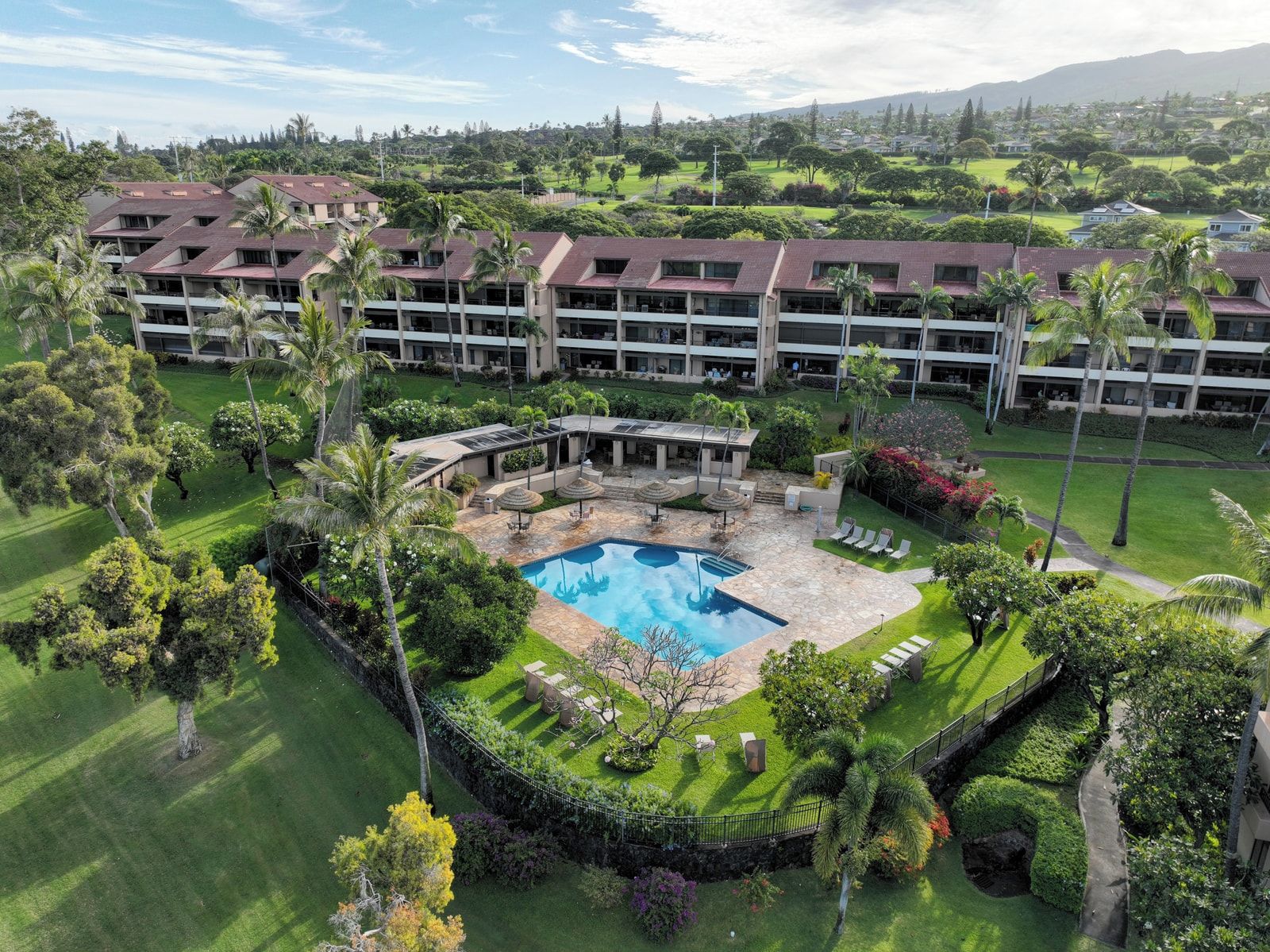 Um resort com piscina central, vários edifícios e paisagismo exuberante.