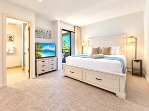 A bedroom with a large bed, a television, a desk, and a view of the outdoors.