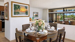 A dining area with a table set for six, surrounded by patterned chairs, with a view of the outdoors.