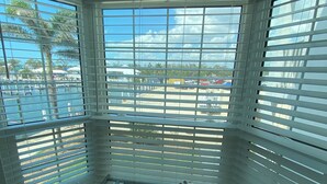 Une chambre d’angle dotée d’une baie vitrée donnant sur un port de plaisance et des palmiers.
