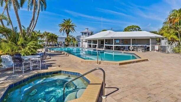 Un espace piscine avec des chaises longues et un coin salon abrité.