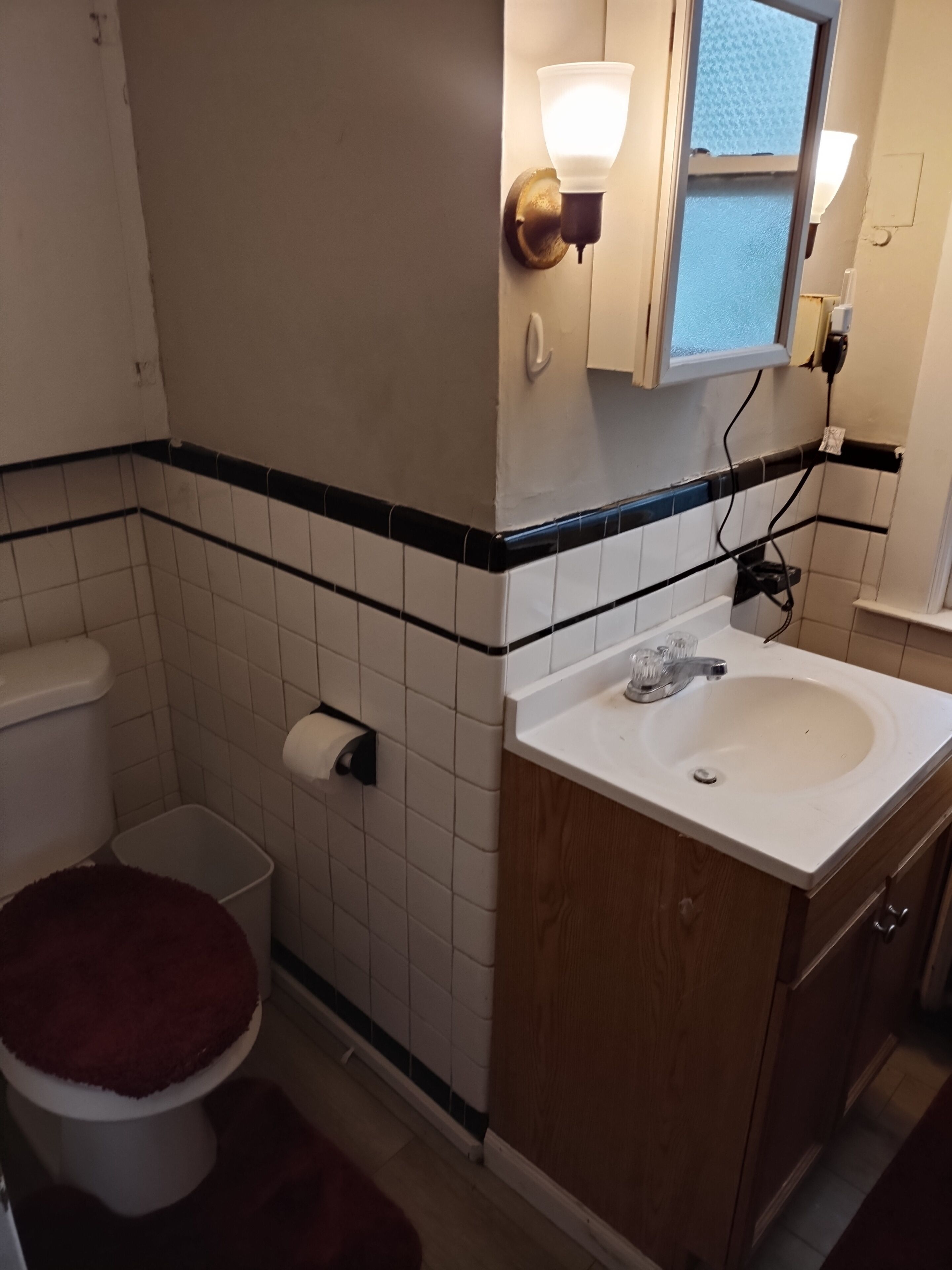 A bathroom with a toilet, sink, and mirror.