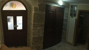 A hallway with a stone wall, a wooden door with frosted glass panels, and a radiator.