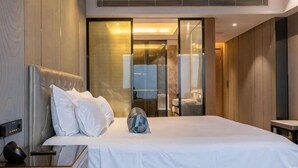 Ein Hotelzimmer mit Bett, Nachttisch und einem großen Spiegel.