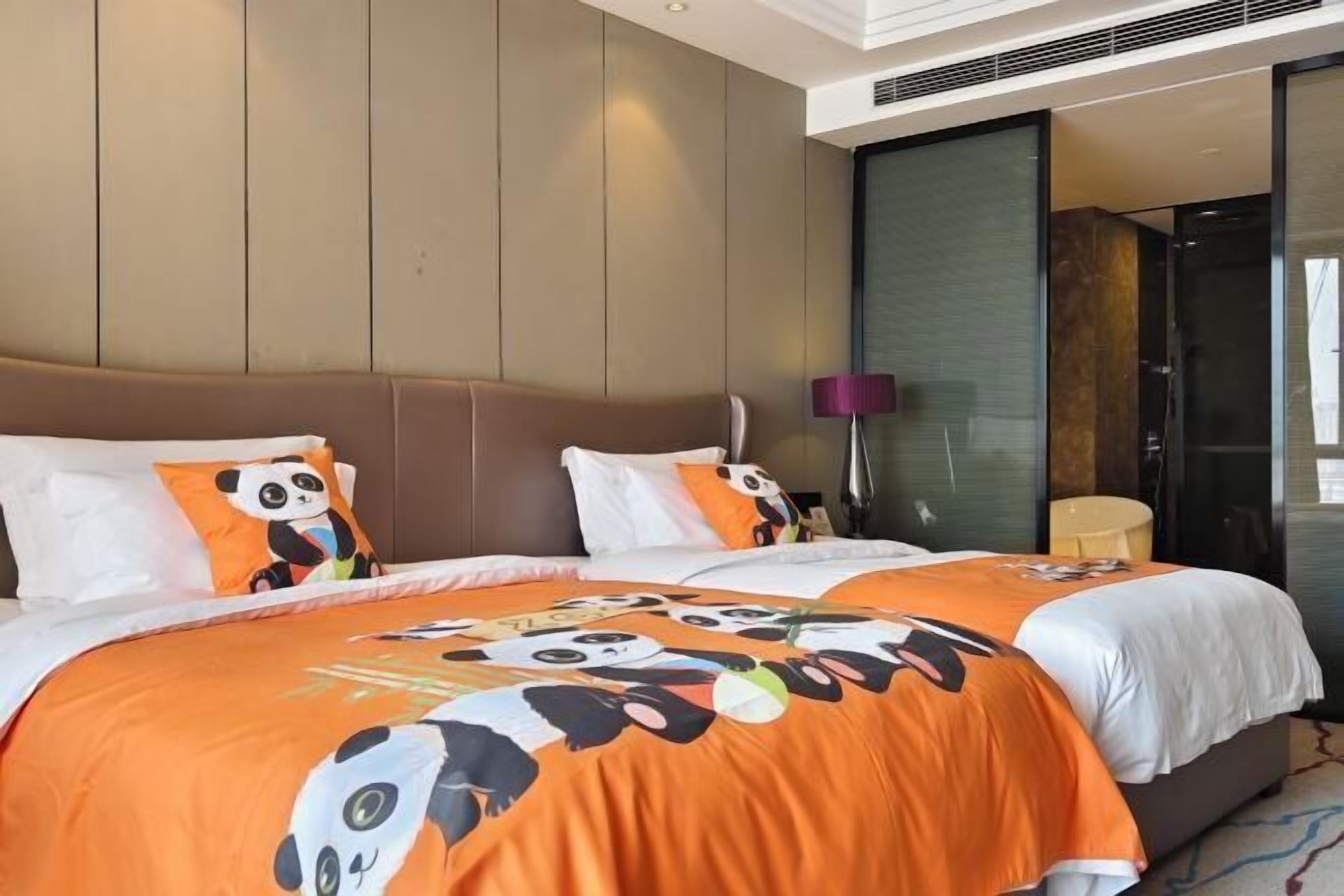 A hotel room with two beds, each with a panda-themed bedspread, a large window, and a modern design.