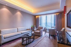 A modern hotel room with a sofa, armchairs, a coffee table, and a TV. - Beishan Hotel (Nantong)