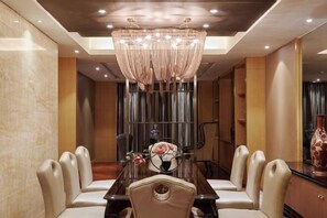 A dining area with a chandelier, a long table, and cushioned chairs. - Beishan Hotel (Nantong)