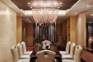 Un comedor con candelabro, una mesa larga y sillas acolchadas.