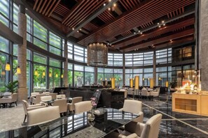 A spacious hotel lobby with a central bar, seating areas, and large windows offering views of greenery. - Beishan Hotel (Nantong)