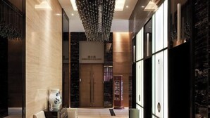 Eine moderne Lobby mit Marmorboden, einer Kristallleuchter, einer Rezeption und einer Bücherwand.