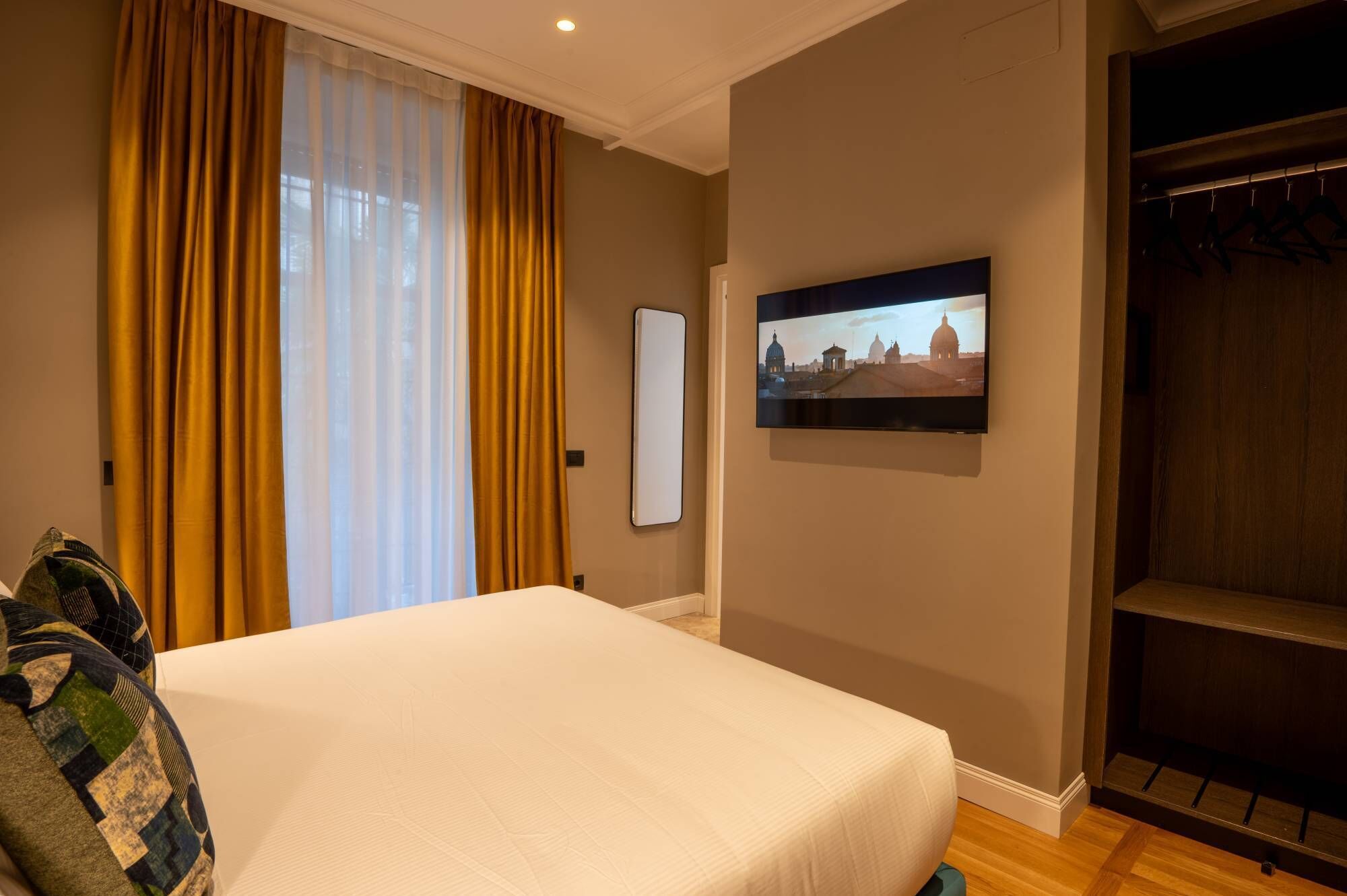 Quarto de hotel com uma cama, televisão fixada na parede e um guarda-roupa.