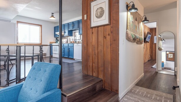 Une cuisine moderne avec des meubles bleus, un coin repas avec une chaise bleue et un escalier menant à un deuxième étage.