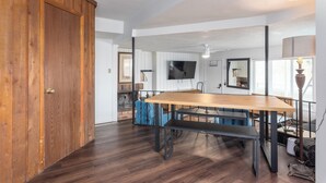 Une pièce spacieuse avec une porte en bois, une grande table à manger en bois et un banc.