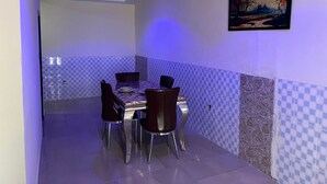 Un coin repas agrémenté d’un mur recouvert de carreaux à motifs géométriques, d’un tableau et d’une table dressée pour quatre personnes.