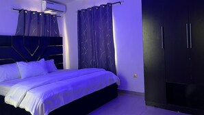 Une chambre moderne avec un lit, une armoire sombre et un appareil de climatisation.