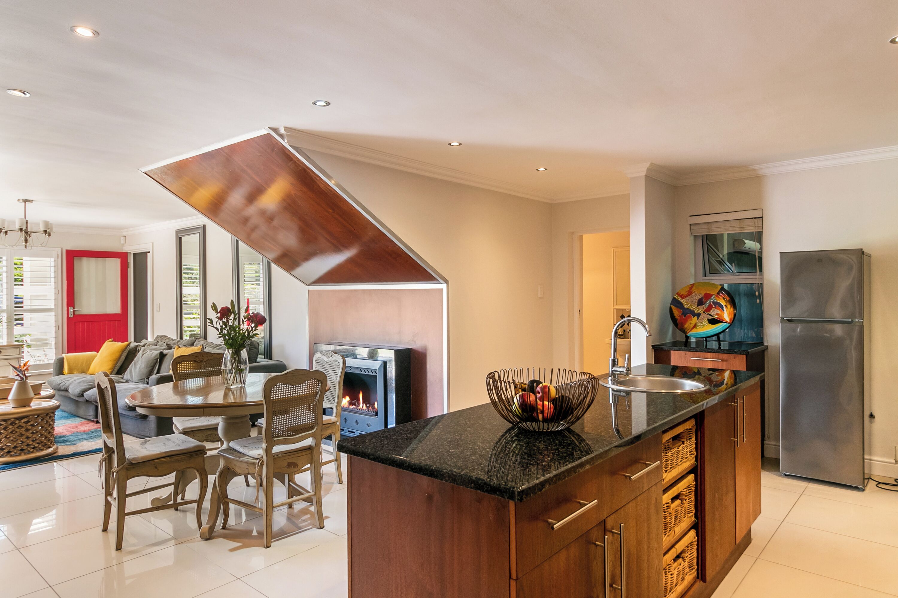 Una cocina moderna con una isla central, armarios de madera y un refrigerador de acero inoxidable.