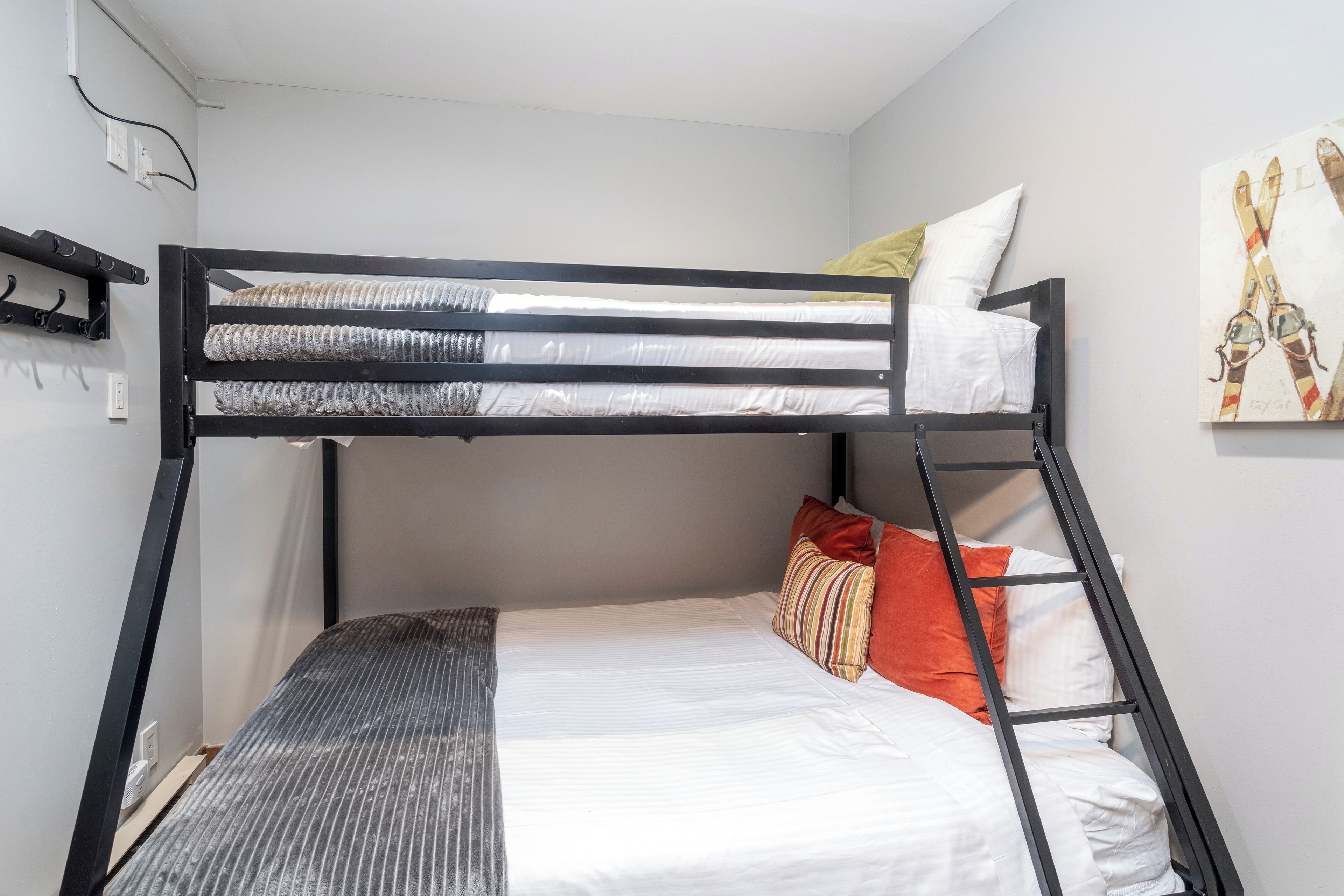 Uma cama beliche com colchão, travesseiros e cabeceira.
