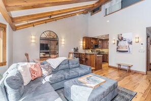 A spacious living area with a sectional sofa, a dining table, and a kitchen in the background. - Walk to Festivals and Lift 7 | Remodeled 3BR Condo | Hot Tub + Garage Parking (Telluride)