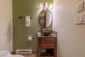 A bathroom with a wooden vanity, a round mirror, and a towel rack.