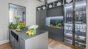 Een moderne keuken met een marmeren aanrecht, een ingebouwd spoelgedeelte en een glazen kast met keukengerei.