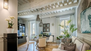 Een ruime woonkamer met een houten vloer, een eethoek met een ronde tafel, en een keuken op de achtergrond.
