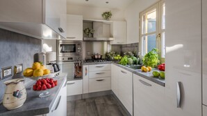 A modern kitchen with stainless steel appliances, white cabinetry, and a window providing natural light. - Elegant Modern Apartment with Terrace in Historic Lucca (Lucca)