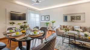 A modern living room with a dining area, a sofa set, a TV mounted on the wall, and a ceiling fan. - Elegant Modern Apartment with Terrace in Historic Lucca (Lucca)