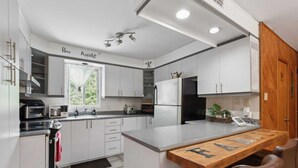 A modern kitchen with white cabinets, a built-in oven, and a wooden island with a chalkboard. - Havre de Détente & Spa (Sainte-Lucie-des-Laurentides)