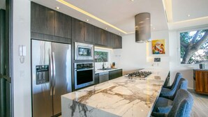 Una cocina moderna con una isla grande, electrodomésticos de acero inoxidable y vistas al exterior.