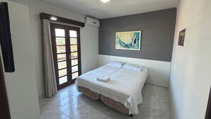 Een slaapkamer met een bed, een plafondventilator, een schilderij en een deur naar een buitenruimte.