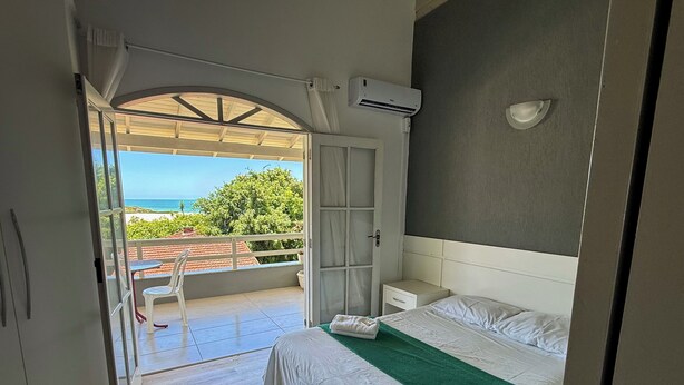Een slaapkamer met een bed, een nachtkastje, een raam met uitzicht op zee en een airconditioning.
