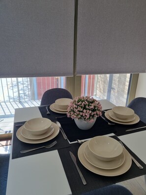 Enjoy meals in this dining area with a table set for four, featuring a central vase and a view of the surrounding cityscape.