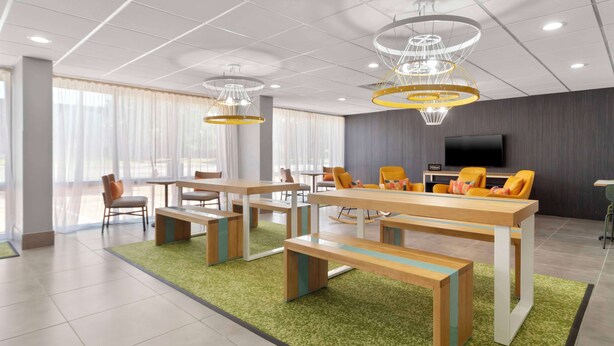 A modern hotel lobby with a large seating area, a flat-screen TV, and a green carpet. - Spark By Hilton Grand Prairie (Grand Prairie)