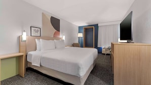 A hotel room with a large bed, bedside tables, a desk, a flat-screen TV, and a window with curtains. - Spark By Hilton Grand Prairie (Grand Prairie)