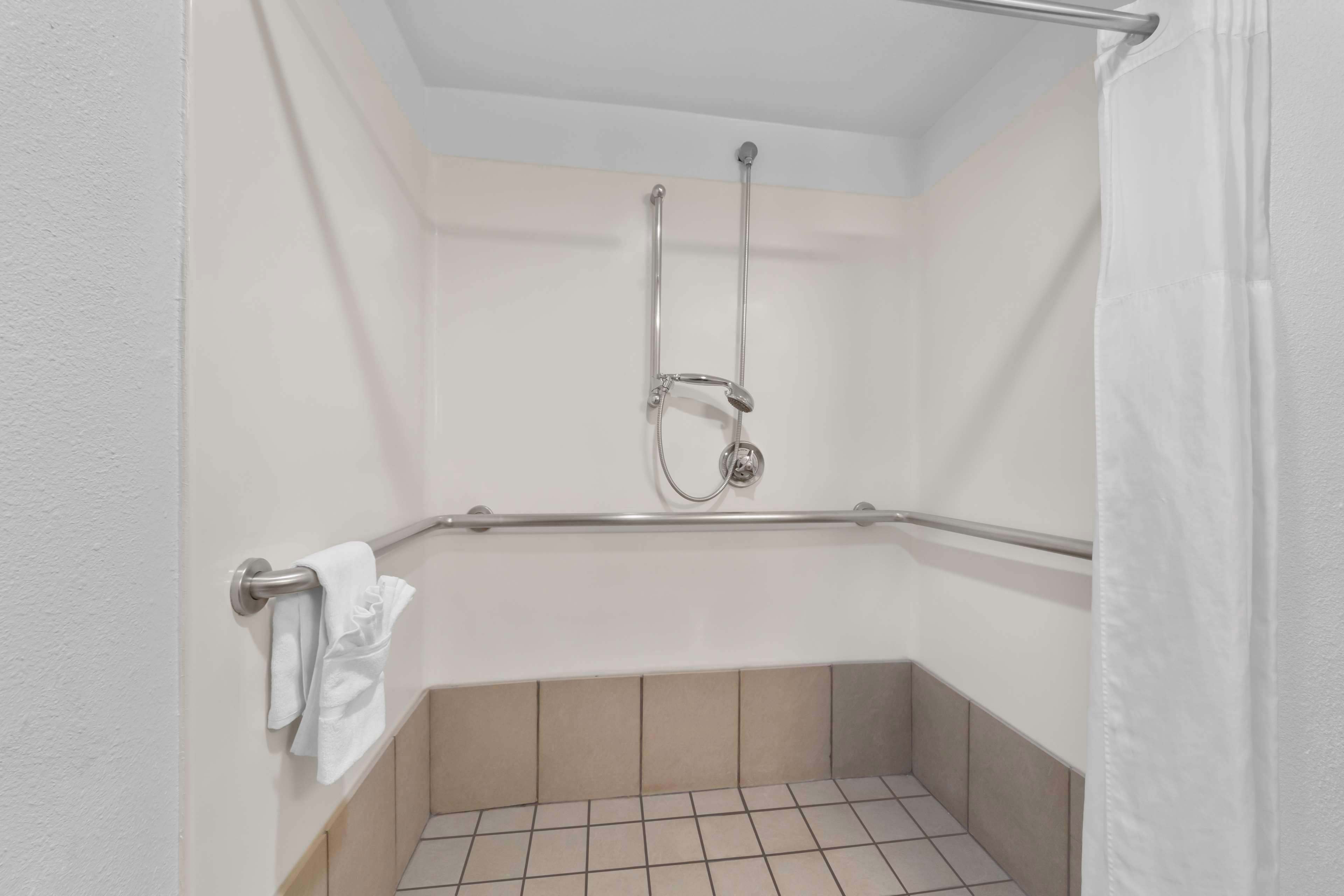 A small, enclosed shower area with a grab bar, a towel rack, and a showerhead.