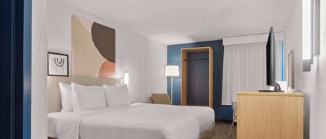 Une chambre d’hôtel avec un grand lit, un bureau, une chaise et un téléviseur.