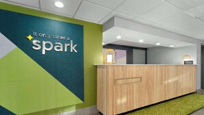 A reception desk with a 'Spark' sign, a wooden counter, and a green carpet. - Spark By Hilton Grand Prairie (Grand Prairie)