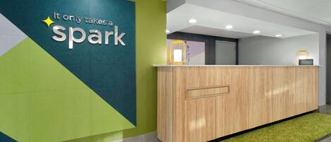 A reception desk with a 'Spark' sign, a wooden counter, and a green carpet.
