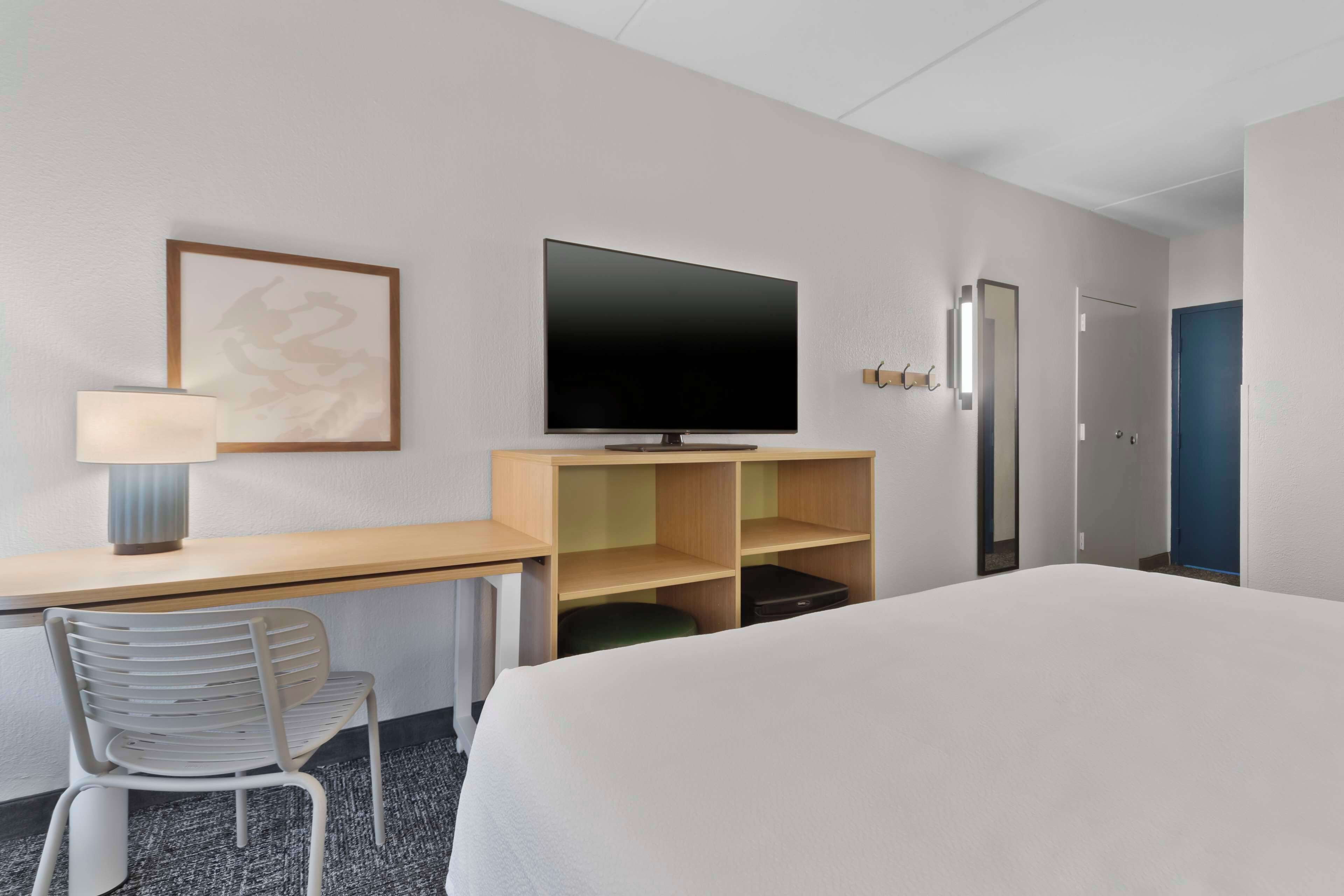 Une chambre d’hôtel comprenant un lit, un bureau avec une chaise, une télévision et une porte.
