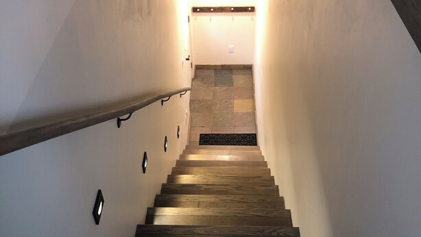 A wooden staircase with a handrail and a light fixture at the top.