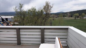 A balcony with a white railing, a wooden table, and a white bench.