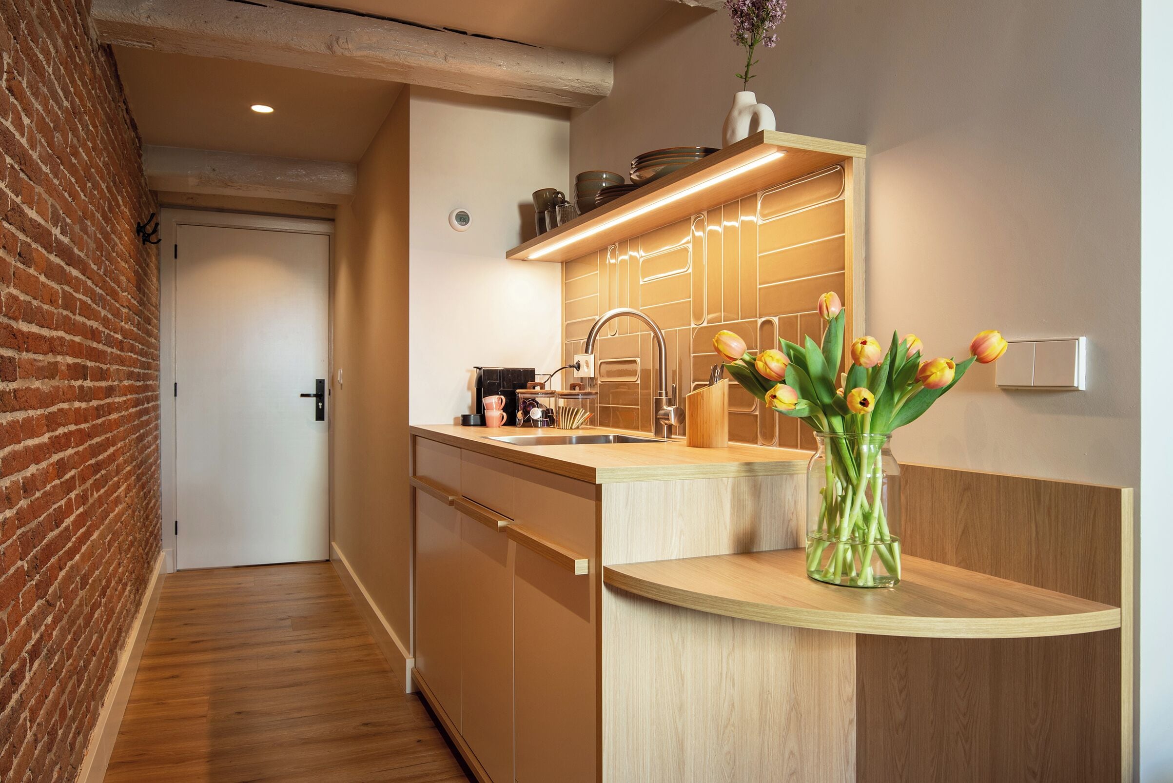 A modern kitchen with a wooden countertop, a sink, and a vase of tulips.