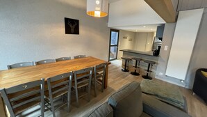 Uma cozinha moderna com uma ilha grande, banquetas e uma mesa de jantar com cadeiras.