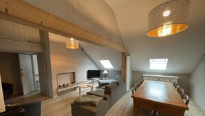 Um apartamento moderno estilo loft, com área de refeições, lareira, televisão e cozinha.