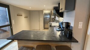 Uma cozinha moderna com uma ilha grande, banquetas e forno embutido.