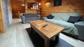 Ein gemütliches Holzhaus-Interieur mit einer Couch, einem Couchtisch und einem Kamin.
